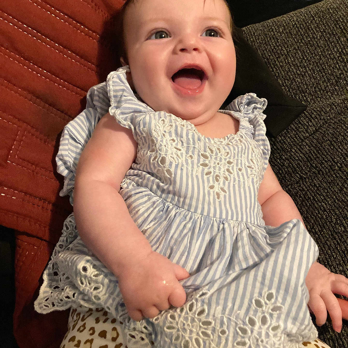 Luna is registered to the contest to win money with this photo: baby, child, smiling, laughing, dress, striped, lace, leopard_print, pants, sitting, couch, cushion, indoor, happy, person, infant, cute, portrait, face, hand