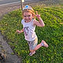 child, girl, tiara, earrings, unicorn_shirt, shorts, grass, sidewalk, peace_sign, smile, playful, daylight, road, traffic_cones, people, shoes, socks, outdoor, sunlight, pose