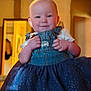 Harley joined the competition — help win amazing prizes! baby, child, smiling, indoor, denim, overalls, dress, tutu, blue, clothing, hands, face, cheeks, warm_lighting, doorway, blurred_background, person, cute, infant, portrait