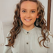 Addison is registered to the contest to win money with this photo: child, girl, smile, portrait, curly_hair, earrings, dress, indoor, buttoned_shirt, young, happy, person, fashion, hairstyle, face, necklace, skin, light, background, casual