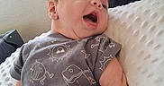 Laidin joined the competition — help win amazing prizes! baby, infant, smiling, gray_shirt, cartoon_prints, pillow, white_pillow, indoor, natural_light, window_blinds, cute, happy, child, person, portrait, relaxing, skin, head, hand, expression