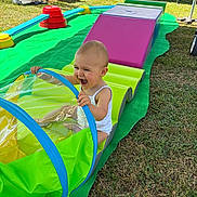Talya a rejoint le concours — aidez-le/la à gagner de superbes lots ! baby, child, clothing, colorful, crawling, fun, grass, green_mat, happy, infant, outdoor, person, plastic_toy, playground, playtime, smiling, summer, sunny, toy, tunnel