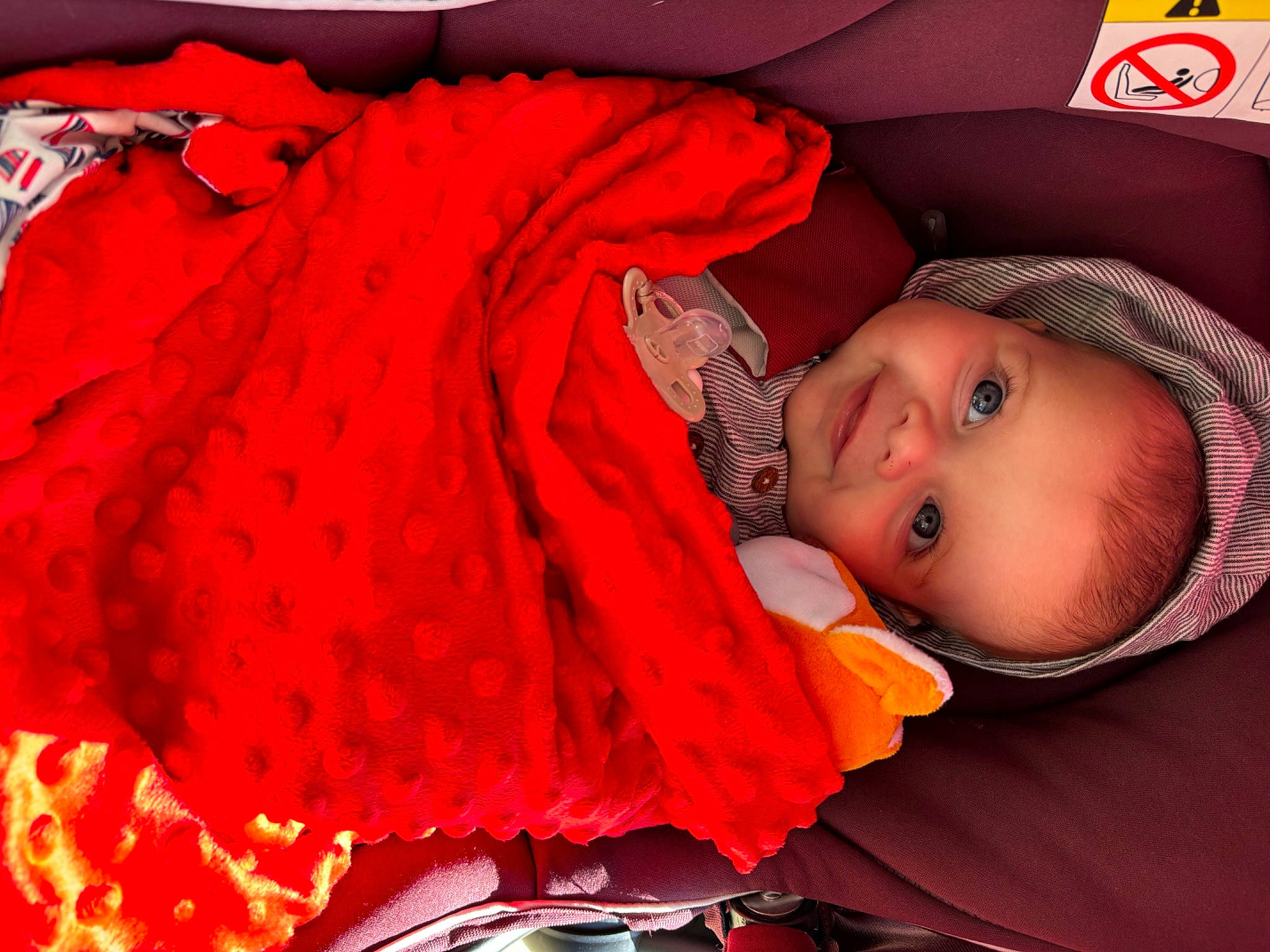 Louis participe au concours pour gagner de l'argent avec cette photo : baby, baby_carriage, baby_products, baby_toddler_clothing, carmine, child, comfort, couch, facial_expression, fashion_accessory, headgear, magenta, orange, pattern, person, pink, product, red, room, sleeve
