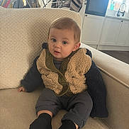 Lennon joined the competition — help win amazing prizes! appliance, baby, black_socks, blanket, child, clothing, couch, cozy, curious, face, furniture, home, indoors, jacket, living_room, modern_kitchen, person, sitting, toddler, window