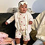 Leya participe au concours pour gagner de l'argent avec cette photo : toddler, child, baby, couch, white_clothing, headband, bow, red_strawberry_prints, shoes, person, indoor, blanket, support, standing, cute, expression, young_child, casual, home, soft_lighting