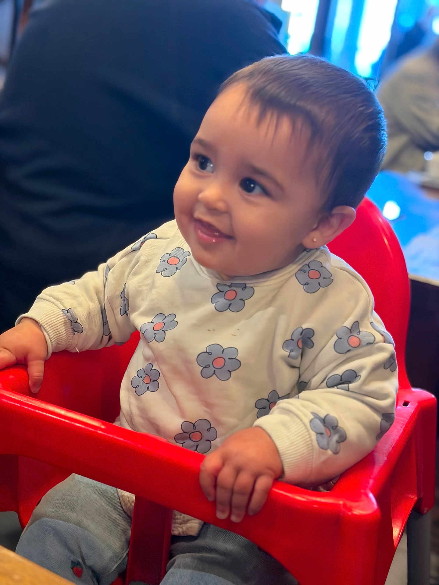 Leya participe au concours pour gagner de l'argent avec cette photo : baby, child, high_chair, smile, sweater, flower_pattern, indoor, cute, happy, person, seated, red, clothing, face, portrait, young_child, hand, table, background_blur, casual
