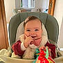 baby, child, clothing, cozy, expression, face, furniture, hand, happy, high_chair, indoor, infant, light, person, playful, seat, smile, toy, warm, window