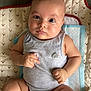 arm, baby, bear_pattern, child, chubby, cute, expression, face, foot, hand, indoor, infant, leg, looking, lying_down, onesie, pattern, quilt, skin, soft_light