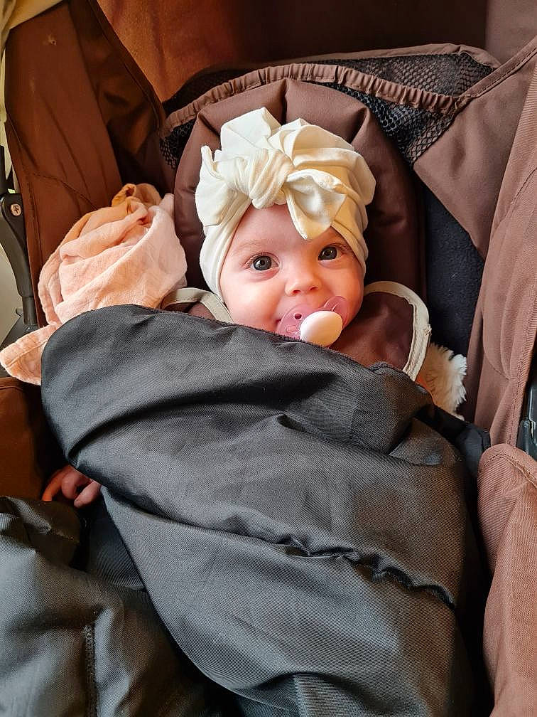 Amaia a rejoint le concours — aidez-le/la à gagner de superbes lots ! baby, baby_carriage, baby_products, baby_safety, baby_sleeping, baby_toddler_clothing, bedding, brown, car_seat, cheek, child, comfort, head, headwear, linens, nap, person, room, sitting, smile