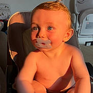 Lyzio a rejoint le concours — aidez-le/la à gagner de superbes lots ! baby, pacifier, child, infant, highchair, sunlight, indoor, curly_hair, blue_eyes, skin, hand, foot, face, cheek, furniture, sitting, toy, room, shelf, cozy