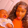 Josiah is registered to the contest to win money with this photo: baby, infant, young_woman, selfie, portrait, faces, tongue_out, funny, smiling, indoor, warm_lighting, orange_tint, long_hair, curly_hair, white_clothing, baby_clothing, bear_design, door, family, close_up