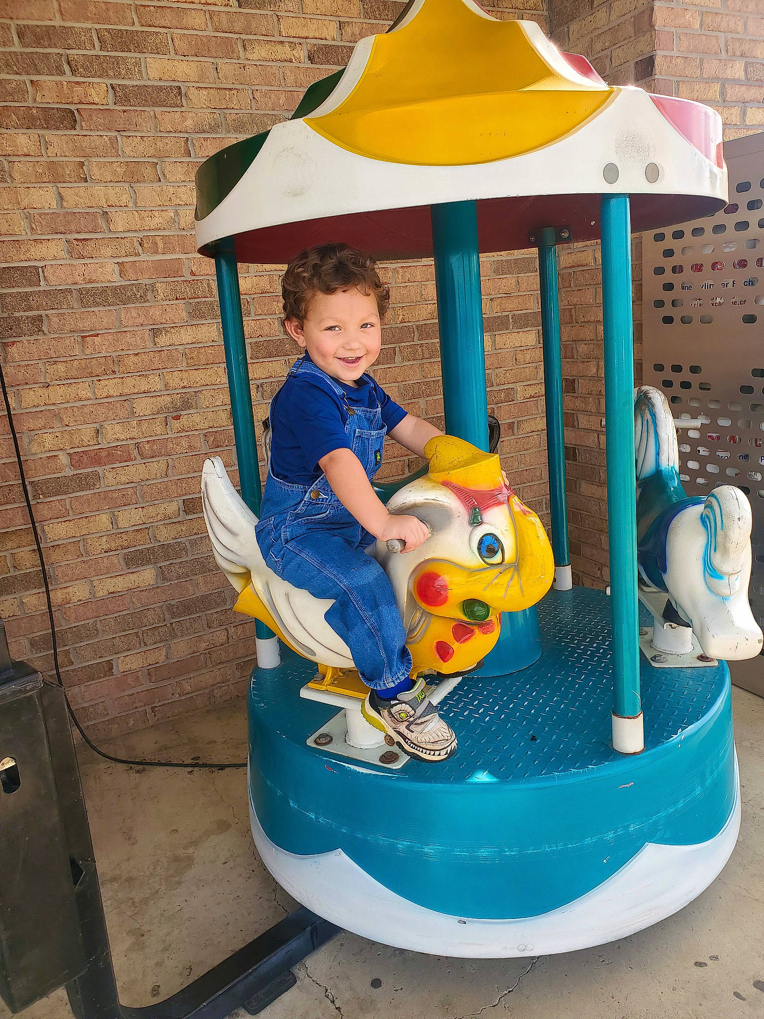 Bear is registered to the contest to win money with this photo: amusement_ride, baby_toddler_clothing, child, chute, city, fun, joy, leisure, outdoor_furniture, outdoor_play_equipment, outdoor_recreation, person, play, playground, playground_slide, public_space, recreation, riding_toy, shade, smile