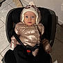 Alba a rejoint le concours — aidez-le/la à gagner de superbes lots ! toddler, child, car_seat, winter_clothing, puffer_jacket, knit_hat, pom_pom, indoor, tile_floor, safety_harness, baby, cute, portrait, warm_clothing, seat, person, small_child, face, looking_at_camera, cozy
