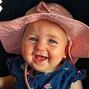 Esther joined the competition — help win amazing prizes! baby, child, smile, blue_eyes, pink_hat, dress, floral_pattern, happy, face, portrait, cute, infant, clothing, headwear, young_child, sitting, indoors, closeup, cheerful, person