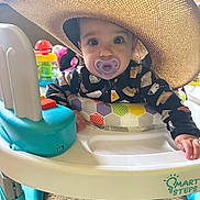 Ivory is registered to the contest to win money with this photo: baby, pacifier, hat, baby_walker, toy, indoor, child, face, clothing, hand, carpet, person, cute, playful, colorful, infant, expression, soft_light, home, smile