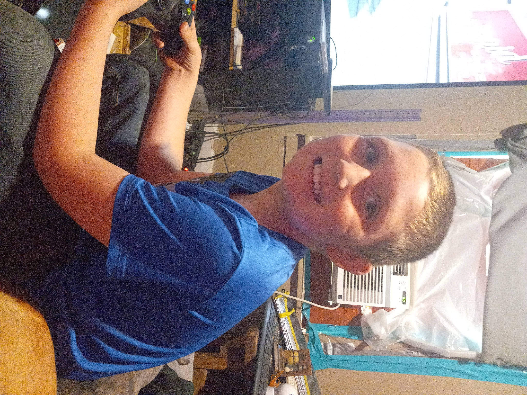 Isaac is registered to the contest to win money with this photo: chest, display_device, elbow, event, eyewear, fun, gesture, happy, jaw, joint, joy, led_backlit_lcd_display, leisure, mouth, person, room, shoulder, smile, t_shirt, television