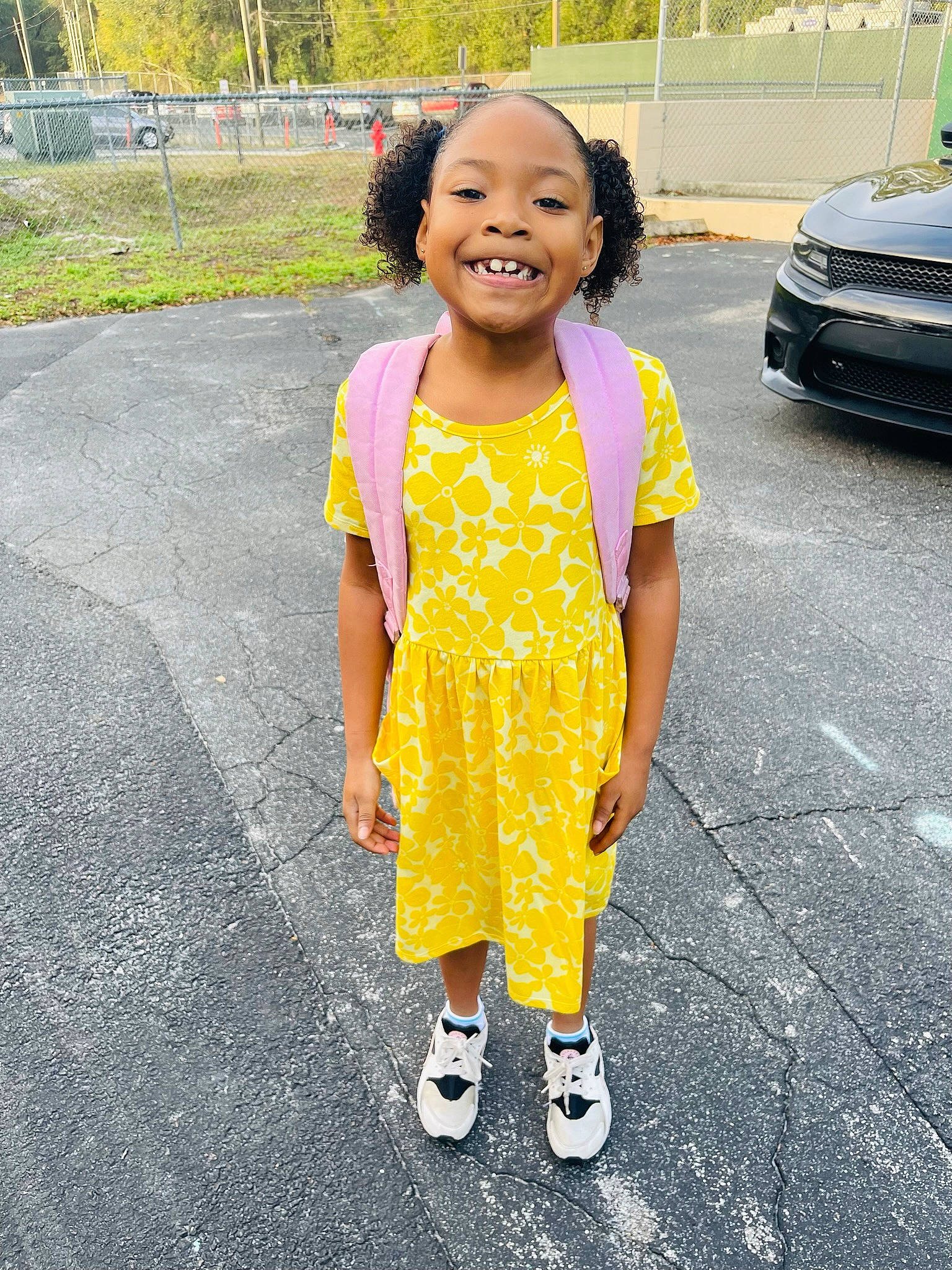 Alyssa is registered to the contest to win money with this photo: asphalt, automotive_lighting, car, child, dress, eye, face, grass, happy, hood, joy, leisure, motor_vehicle, person, road, road_surface, sidewalk, smile, t_shirt, toddler