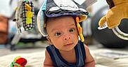 Matteo Ace joined the competition — help win amazing prizes! baby, infant, toy, plush, colorful, face, eyes, indoor, soft, fabric, playful, child, cute, curious, lying_down, close_up, headwear, bright, background_blur, person