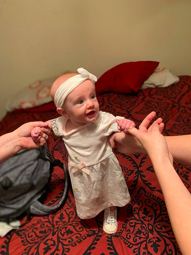 Arizona is registered to the contest to win money with this photo: baby, baby_toddler_clothing, child, comfort, couch, event, flooring, fun, happy, hat, headwear, human_body, linens, magenta, peach, person, pink, sitting, skin, sleeve