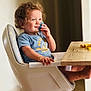 Swan a rejoint le concours — aidez-le/la à gagner de superbes lots ! toddler, child, high_chair, pacifier, smile, curly_hair, blue_shirt, indoor, wooden_table, snack, happy, sitting, furniture, baby, cute, face, hand, foot, light, home