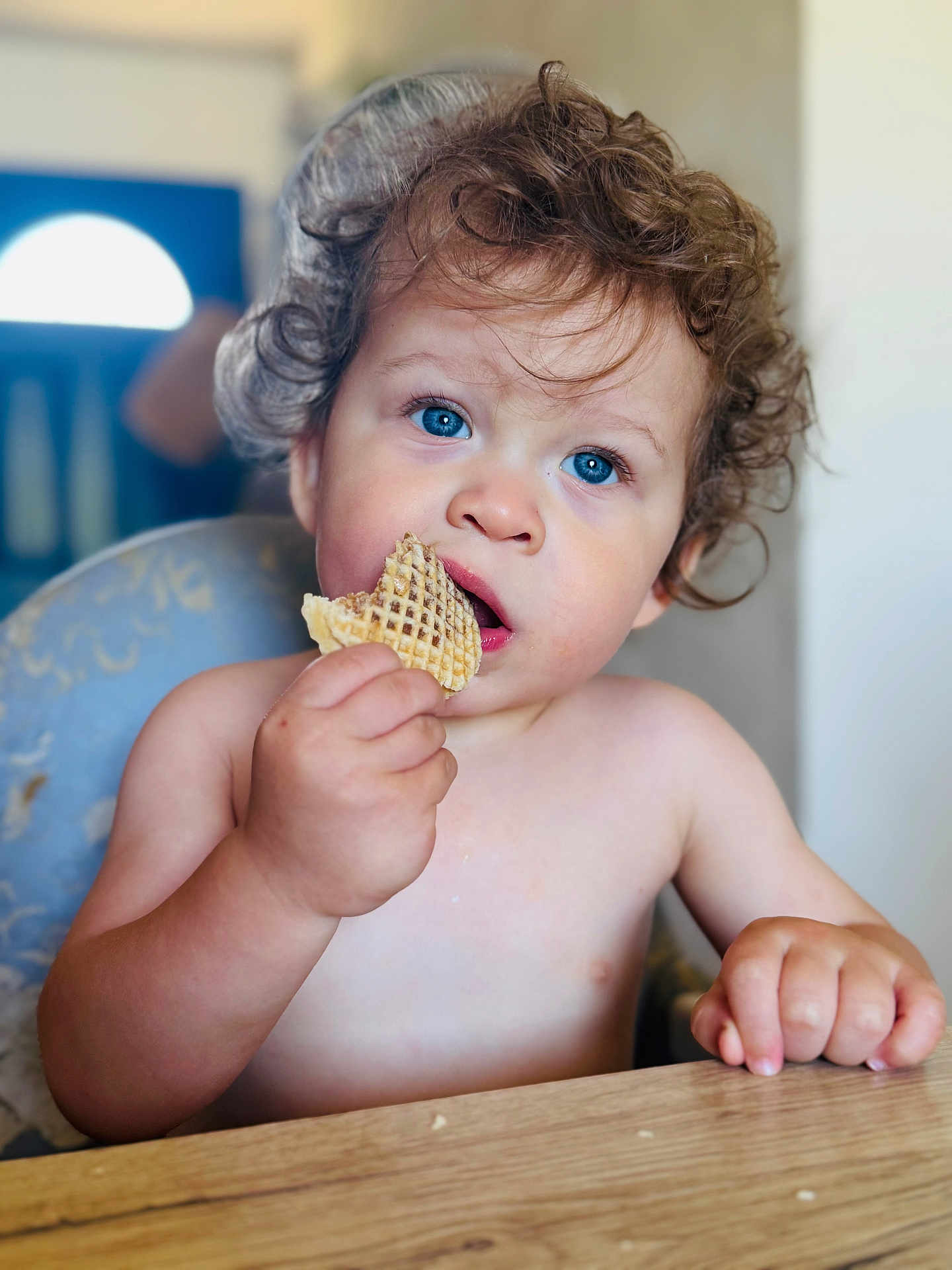 Swan participe au concours pour gagner de l'argent avec cette photo : toddler, child, blue_eyes, curly_hair, snack, waffle, table, hand, face, portrait, indoor, eating, cute, person, skin, expression, young_child, curly, mouth, sitting