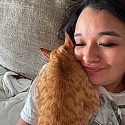 Koda is registered to the contest to win money with this photo: affection, casual_clothing, cat, close_up, closed_eyes, comfort, couch, cozy, fur, happy, home, human_face, indoor, love, orange_tabby, person, pet, relaxation, resting, snuggling