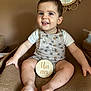 Ezio participe au concours pour gagner de l'argent avec cette photo : baby, child, smiling, romper, white_shirt, wooden_sign, indoor, mirror, window, cushion, seated, happy, cute, one_year_old, skin, feet, hands, decor, portrait, infant