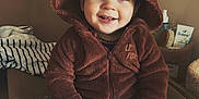 Ezio a rejoint le concours — aidez-le/la à gagner de superbes lots ! baby, child, smiling, hooded_clothing, brown_onesie, fox_costume, indoor, cushion, mirror, toiletries, happy, cute, portrait, sitting, cozy, furniture, hand_jewelry, face, person, warm_lighting