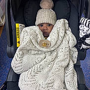 Amari joined the competition — help win amazing prizes! baby, infant, car_seat, blanket, knitwear, hat, pom_pom, pacifier, child, indoors, clothing, seat, bundle, cute, face, person, warm, comfort, portrait, newborn
