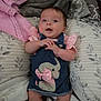 baby, infant, denim_dress, elephant_applique, pink_clothing, blanket, pillow, bed, soft_texture, cozy, child, cute, indoors, fabric, sleepwear, person, smiling, young_child, lying_down, comfortable