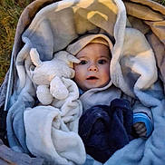 Romain a rejoint le concours — aidez-le/la à gagner de superbes lots ! baby, blanket, plush_toy, stroller, outdoor, soft_texture, child, cute, warm, wrapped, face, blue_clothing, comfort, expression, toy, infant, cozy, person, nest, curious