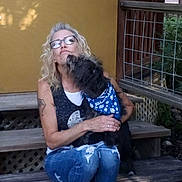 Harley is registered to the contest to win money with this photo: affection, bench, blue_bandana, casual, daylight, dog, fence, glasses, happy, jeans, leash, nature, outdoor, pet, sitting, smiling, steps, tattoo, woman, yellow_wall