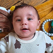 Islam a rejoint le concours — aidez-le/la à gagner de superbes lots ! baby, infant, face, smile, eyes, sweater, patterned_clothing, blanket, toy, beads, wood_floor, closeup, lying_down, child, cute, indoors, portrait, happy, soft_focus, warm_colors