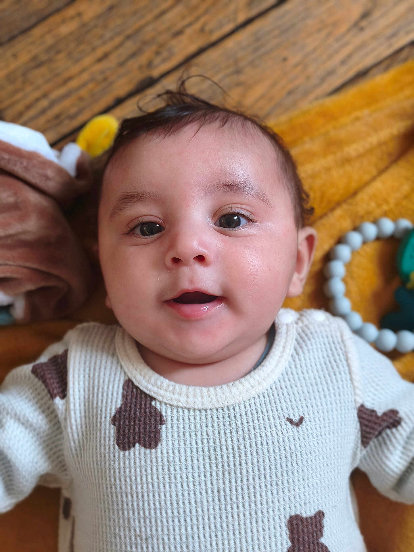 Islam a rejoint le concours — aidez-le/la à gagner de superbes lots ! baby, infant, face, smile, eyes, sweater, patterned_clothing, blanket, toy, beads, wood_floor, closeup, lying_down, child, cute, indoors, portrait, happy, soft_focus, warm_colors