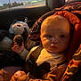baby, car_seat, child, toy, stuffed_animal, seatbelt, window, night, light, indoor, car_interior, clothing, infant, cute, portrait, sitting, face, hand, travel, safety