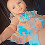 baby, infant, child, blue_eyes, floral_dress, colorful_clothing, blanket, lying_down, soft_lighting, indoor, cute, calm, portrait, skin, person, young_child, diaper, baby_girl, closeup, relaxed
