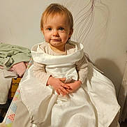 Louanna participe au concours pour gagner de l'argent avec cette photo : baby, child, clothing, cushion, cute, decor, fabric, floor, furniture, hands, home, indoor, person, portrait, sitting, smile, toddler, towel, wall, white_dress