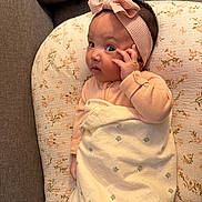 Maryam joined the competition — help win amazing prizes! baby, infant, blanket, headband, couch, floral_pattern, expression, curious, face, hand, child, indoors, cozy, pink, soft_furnishing, portrait, cute, person, resting, wrapped
