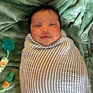 Maaer joined the competition — help win amazing prizes! baby, swaddle, blanket, pacifier, clip, infant, smile, face, lying_down, green_blanket, striped_cloth, newborn, cute, child, soft_texture, indoors, closeup, head, resting, comfort