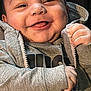 Scooter is registered to the contest to win money with this photo: baby, smiling, happy, tongue_out, hoodie, grey_clothing, infant, closeup, cute, child, face, hand, zipped_jacket, casual, warm, portrait, indoors, skin, young, person