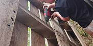 Kolton Knight joined the competition — help win amazing prizes! activity, black_shirt, blonde_hair, car, child, construction, daylight, grass, kid, outdoor, person, playing, power_drill, shorts, side_view, summer, tool, wooden_pallet, working, yard