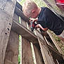 activity, black_shirt, blonde_hair, car, child, construction, daylight, grass, kid, outdoor, person, playing, power_drill, shorts, side_view, summer, tool, wooden_pallet, working, yard