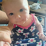 Delilah Rose Knight joined the competition — help win amazing prizes! baby, child, infant, person, dress, flower_pattern, hand, skin, face, eyes, indoor, furniture, table, clothing, cute, holding, closeup, pink, blue, smile