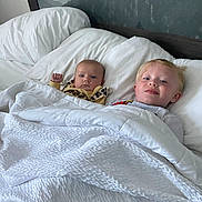 Delilah Rose Knight is registered to the contest to win money with this photo: baby, bed, blanket, child, comfort, cozy, cute, face, head, home, indoor, pillow, portrait, resting, sibling, sleepwear, smile, tucked_in, white, young