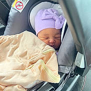 Suzan joined the competition — help win amazing prizes! newborn, baby, sleeping, infant, car_seat, hat, lavender_hat, blanket, bundled, peaceful, face, portrait, indoors, vehicle, travel, safety_label, harness, soft_blanket, resting, cozy