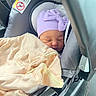 newborn, baby, sleeping, infant, car_seat, hat, lavender_hat, blanket, bundled, peaceful, face, portrait, indoors, vehicle, travel, safety_label, harness, soft_blanket, resting, cozy