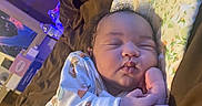 Suzan is registered to the contest to win money with this photo: baby, infant, sleeping, portrait, face, hands, finger, onesie, patterned_clothing, pillow, bed, blanket, indoors, cozy, purple_lighting, home, relaxed, cute, newborn, photography