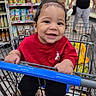 baby, child, smiling, grocery_store, shopping_cart, red_shirt, black_pants, sneakers, supermarket, shelves, food, snacks, shopping, portrait, indoor, happy, sitting, infant, adult, cart