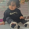 Kaleb is registered to the contest to win money with this photo: child, toddler, curly_hair, sitting, portrait, smiling, black_hoodie, sneakers, shoes, nike, indoor, bench, flowers, pink_wall, window, fashion, casual_clothing, playful, happy, photograph