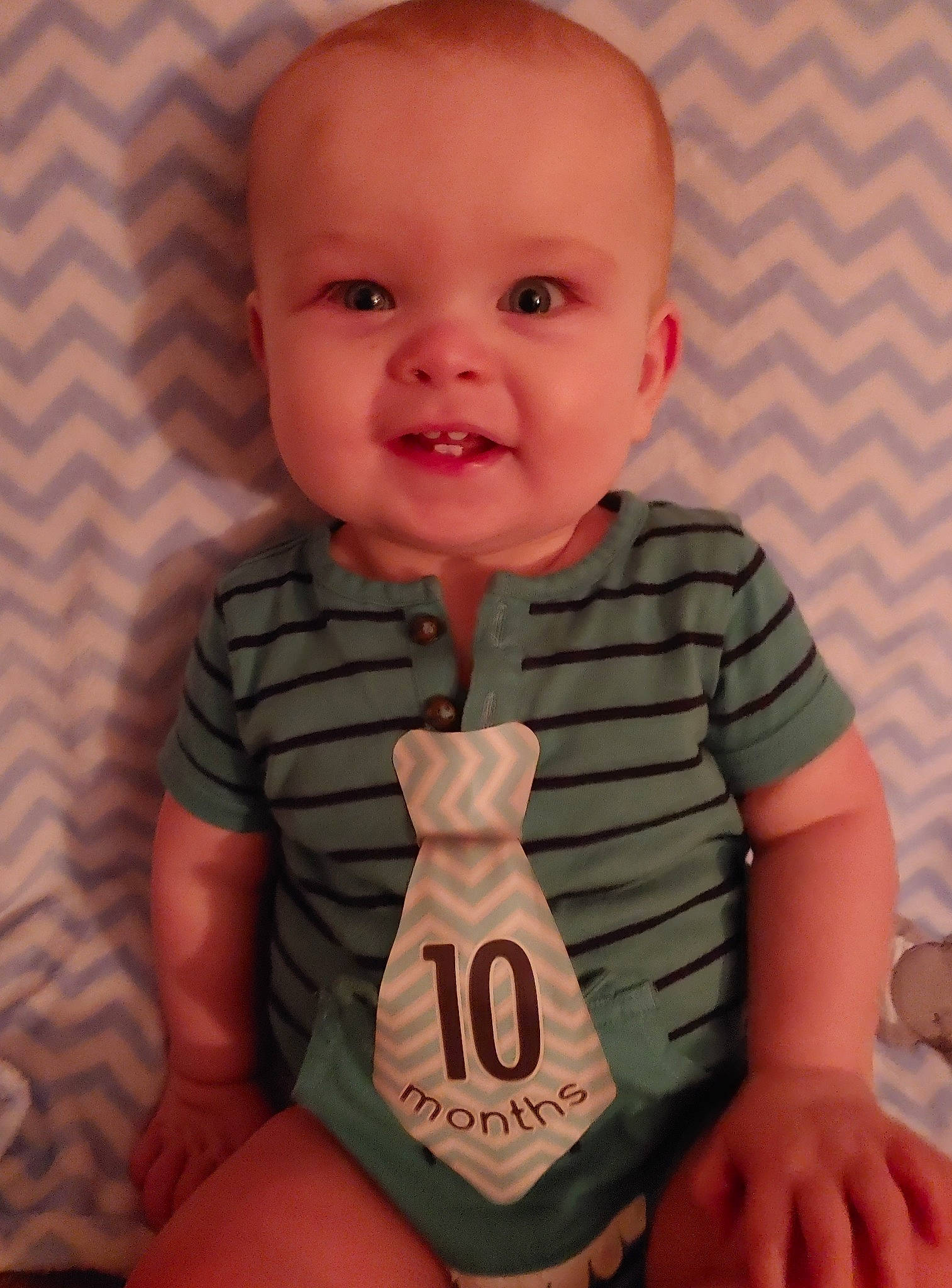 Caiden is registered to the contest to win money with this photo: arm, baby, baby_toddler_clothing, cheek, child, chin, face, finger, hand, head, mouth, muscle, person, sitting, sleeve, smile, standing, thumb, toddler